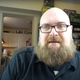Mike Fahey of Kotaku looks toward the camera while sitting at his desk.